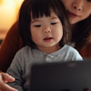 Closeup of mother and her toddler daughter talking with doctor on video call with digital tablet.