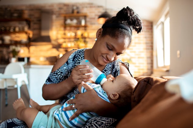 a mother feeding her baby boy with a bottle of milk, in an article about reasons why you stop breast...