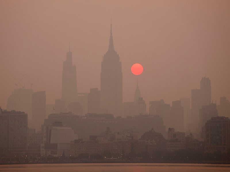 JERSEY CITY, NJ - JUNE 8: The sun is shrouded as it rises in a smokey sky behind the Empire State Bu...