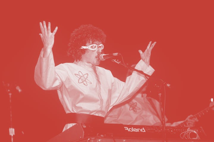 Weird Al Yankovic, wearing a yellow jumpsuit, singing the song "Dare To Be Stupid," a tribute to the...