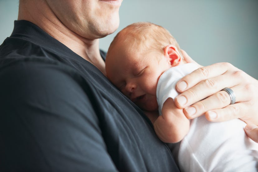 a father snuggling his newborn baby in a list of father's day Instagram captions.