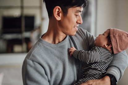 Smiling Asian father shot holding his baby in a list of instagram captions for first father's day