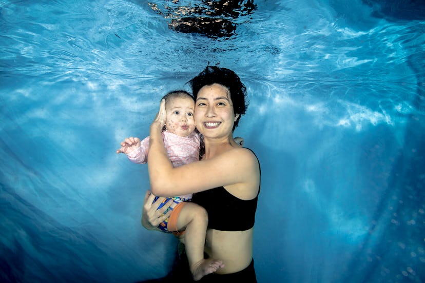 Mom and daughter swim underwater in a pool