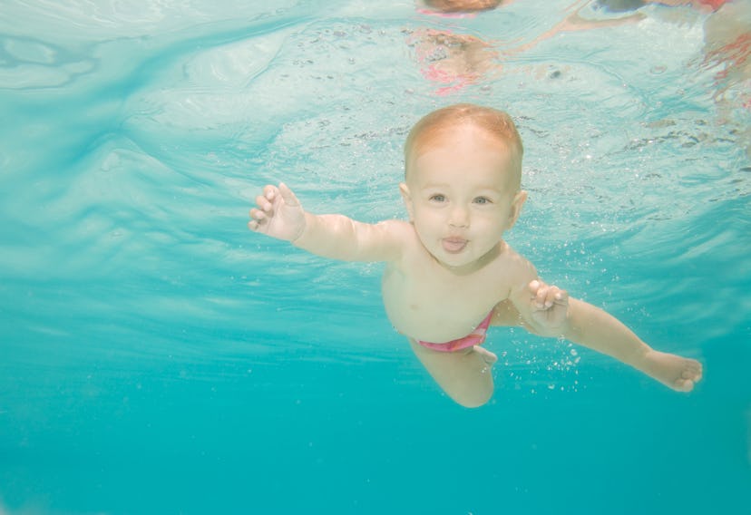baby boy sticks out tongue while swimming underwater