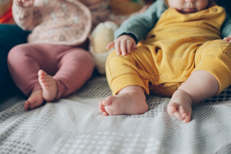 Cute twin boy and girl babies portrait lying on bed, cut-out, only bodies and leggs