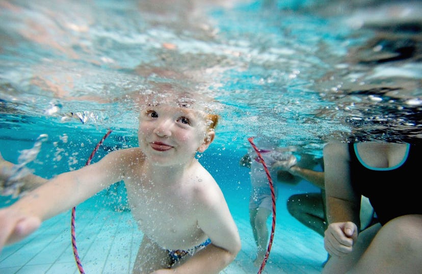 An Australian toddler swims through a hoop underwater during a swimming class for babies