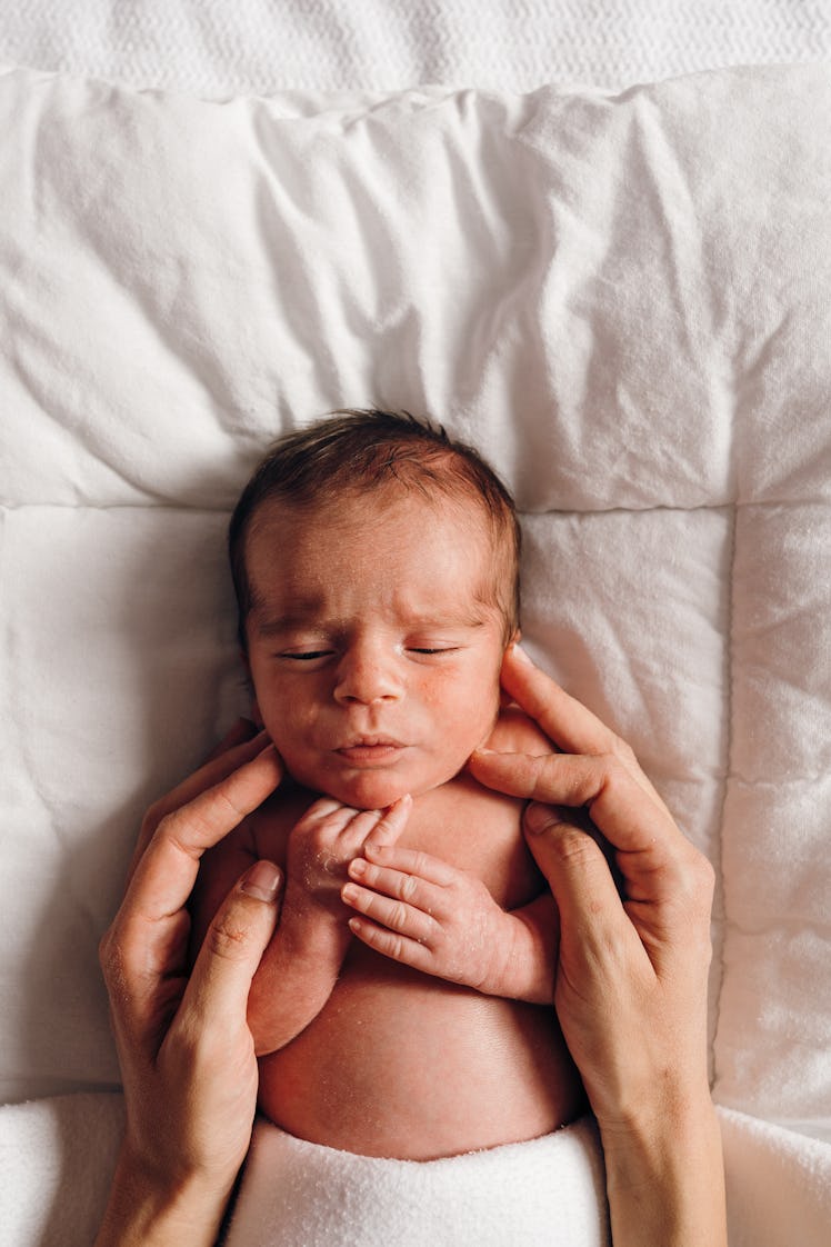 Above shot of a newborn baby and mother calming him with her hand