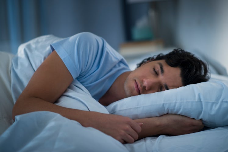 A man is asleep in bed with a blue t-shirt