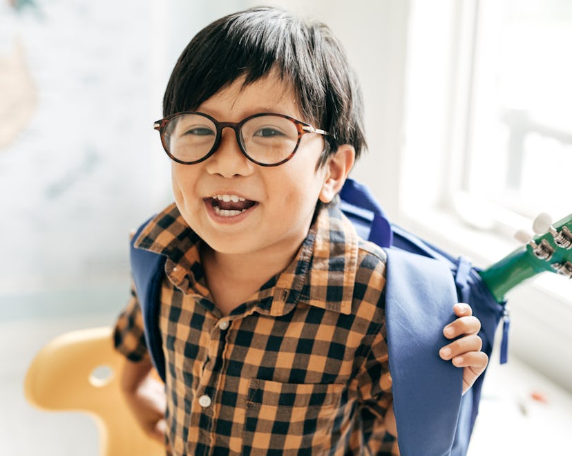 Smiling boy with backpack and favourite guitar in article about photo captions for kindergarten