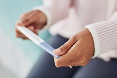 Woman's hands holding pregnancy test, in a story about when to see a fertility specialist