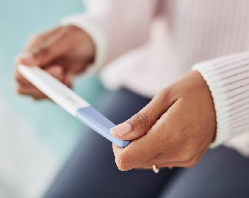 Woman's hands holding pregnancy test, in a story about when to see a fertility specialist