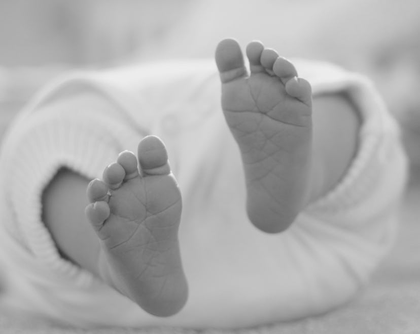 Small feet of a new born baby from below in roundup of baby foot print tattoo ideas
