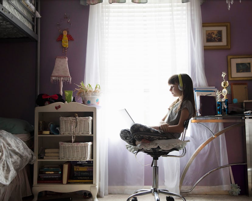Young girl being homeschooled studying through technology at home