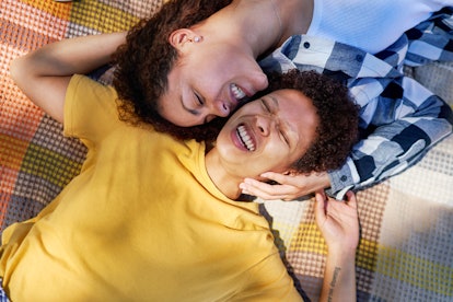 young couple lays on blanket as they consider their August 2023 horoscope