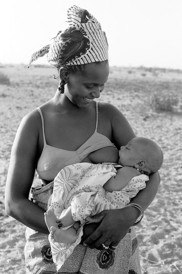 Smiling woman breastfeeding her baby in 1986 in vallée du Ferlo, Sénégal.  
