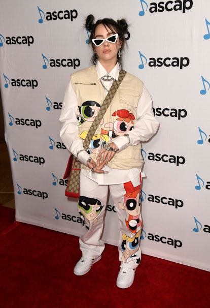 Billie Eilish wears a utility vest and pants with a Powerpuff Girls print, a button-down, Gucci cros...