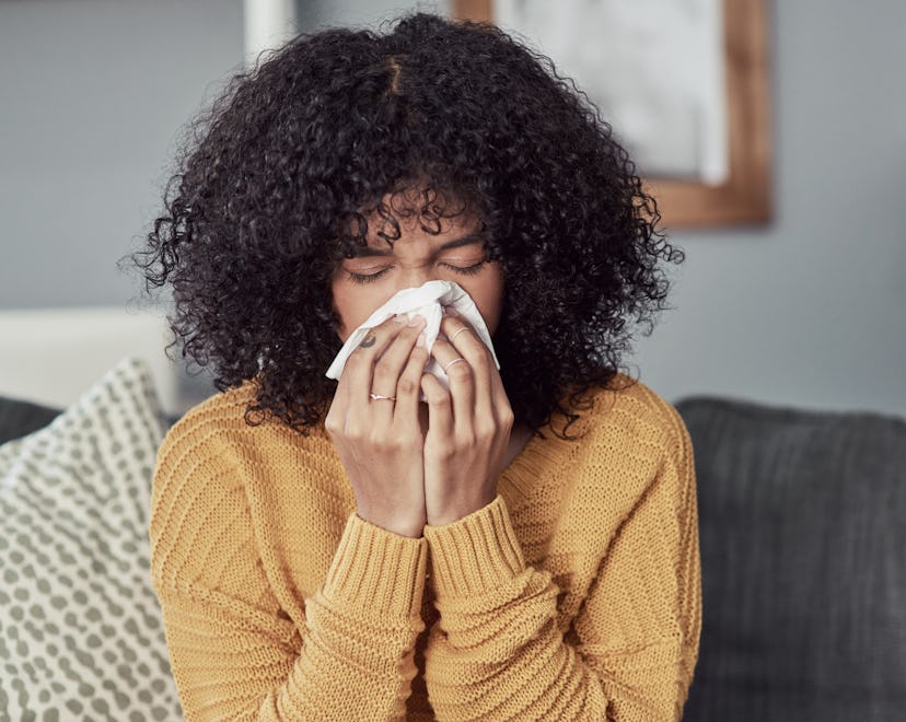 Shot of a young woman blowing her nose with a tissue at home, is a cold a sign of pregnancy?
