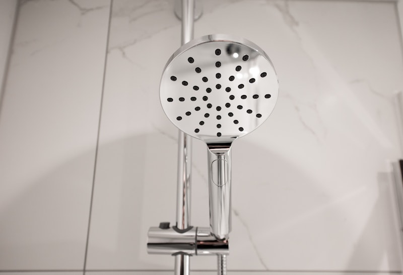 A round chrome shower head in a bathroom