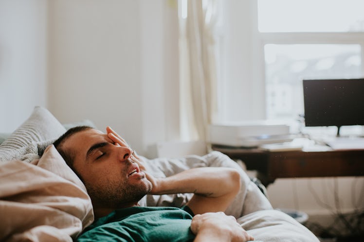 A man has just woken up in a domestic environment, either a living room or a bedroom. He is cozy in ...