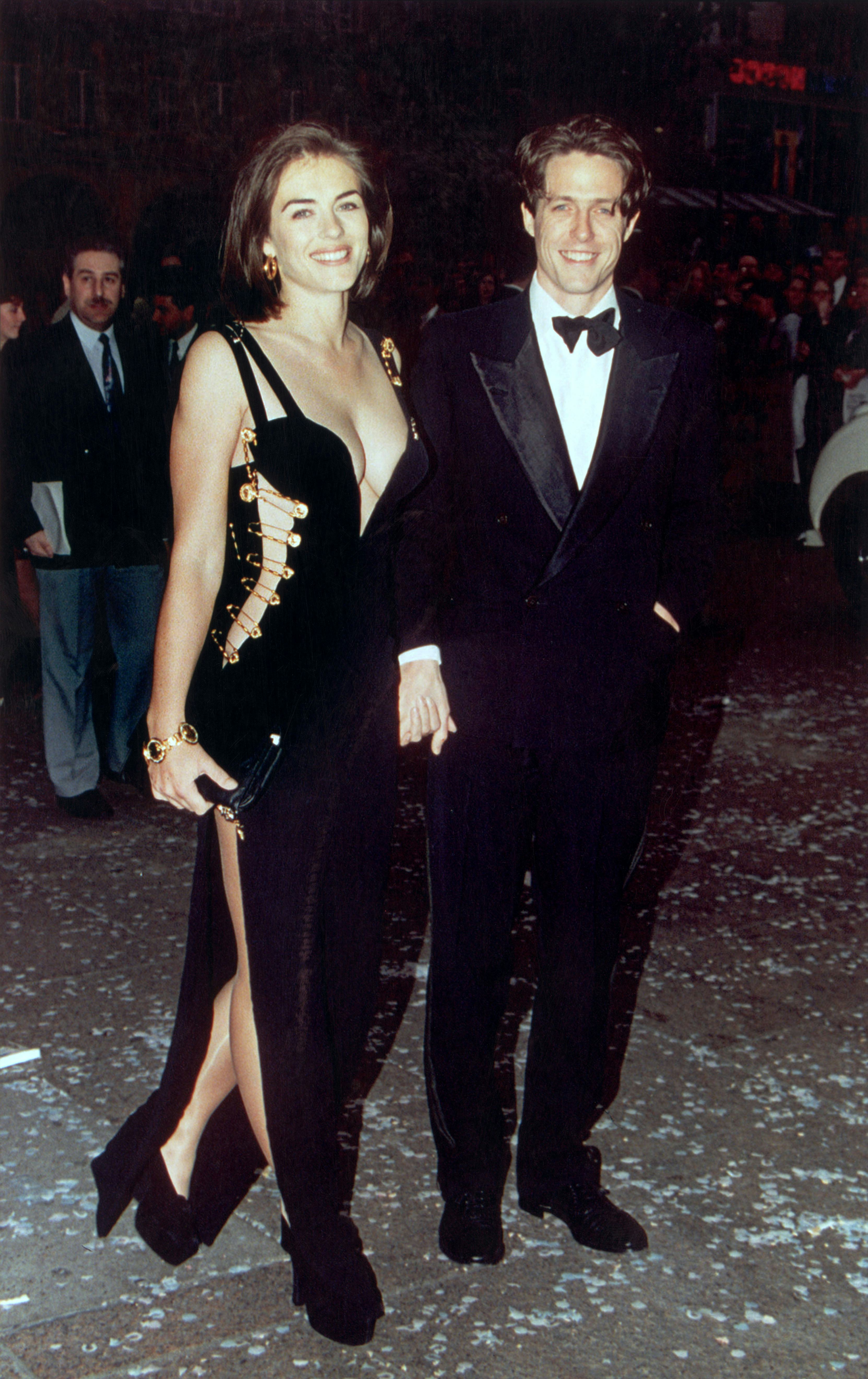 Elizabeth Hurley wears a Versace cut-out dress with Hugh Grant.