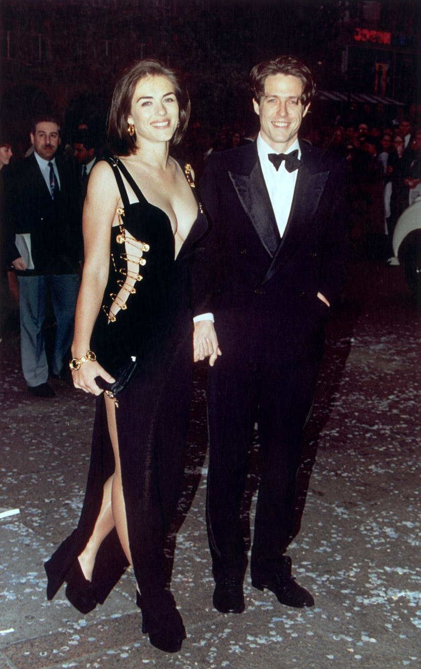 Elizabeth Hurley wears a Versace cut-out dress with Hugh Grant. 