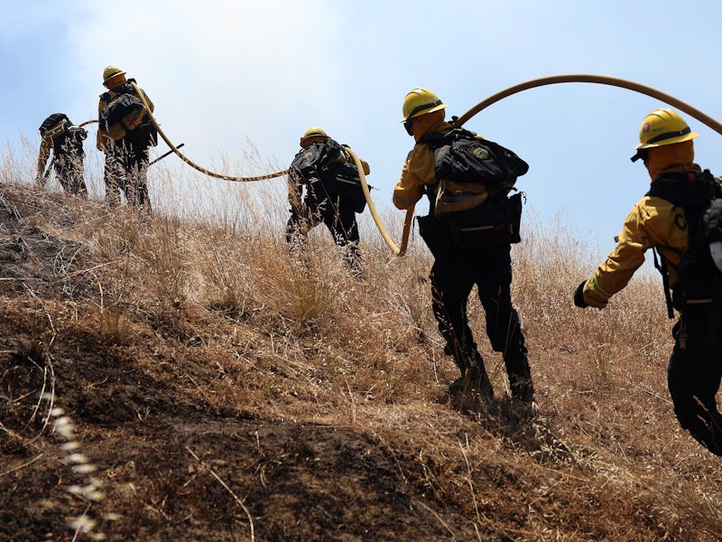 SAN RAFAEL, CALIFORNIA - JUNE 16: Marin County firefighters pull a hose up a hill during a controlle...