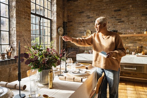 Black female in her 30s putting finishing touches to her table set for Christmas lunch