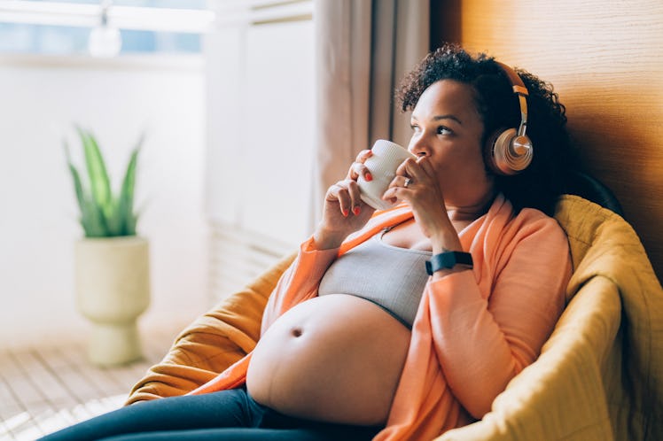 Pregnant woman at home looking through the window