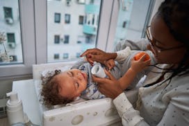 Caring single mother applying baby eczema lotion on her baby boy