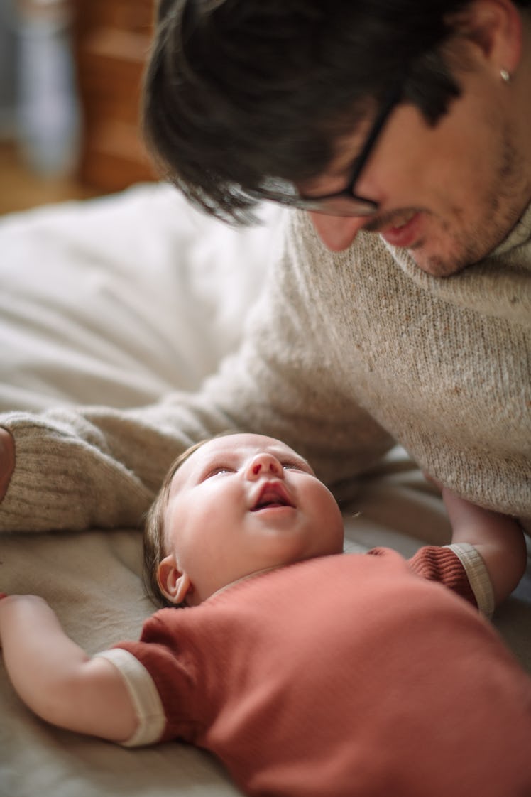 A dad looking down at his newborn baby on a bed.