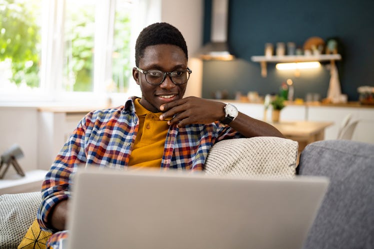 A man working from home on his laptop while sitting on a couch.