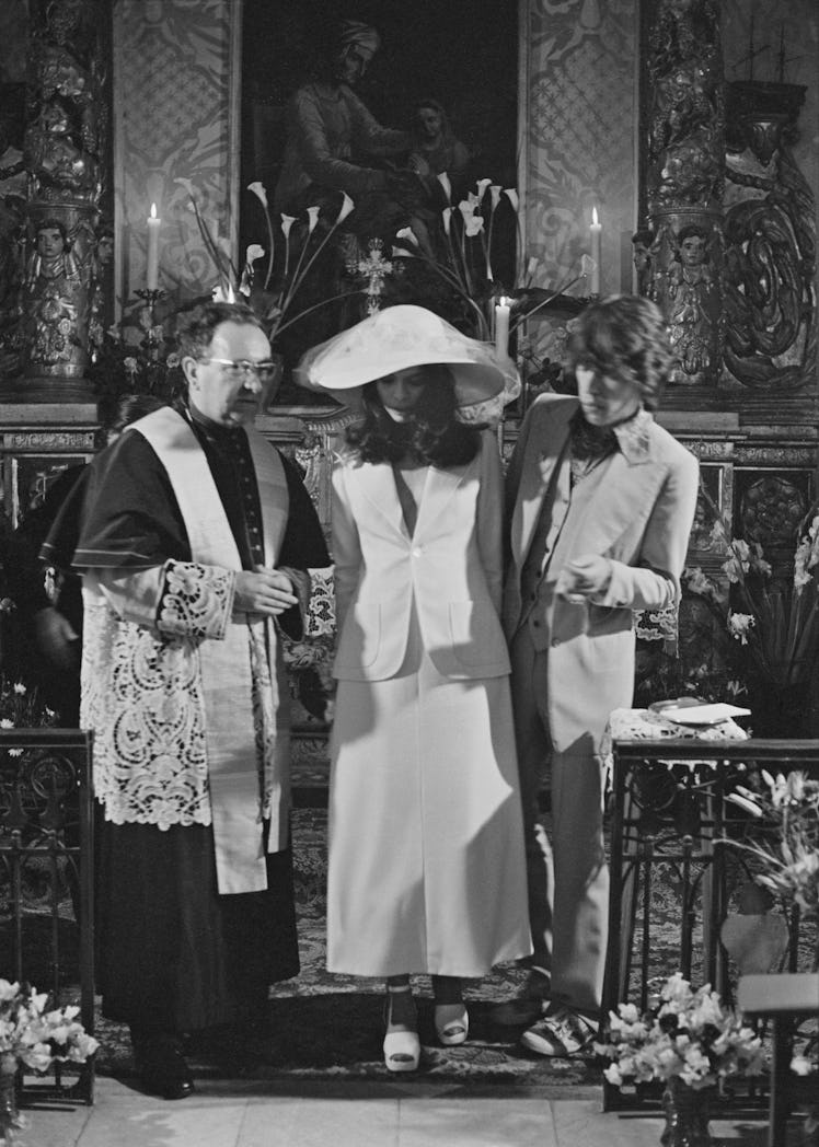 Mick and Bianca Jagger with the officiating priest at their wedding at the Church of St. Anne, St Tr...