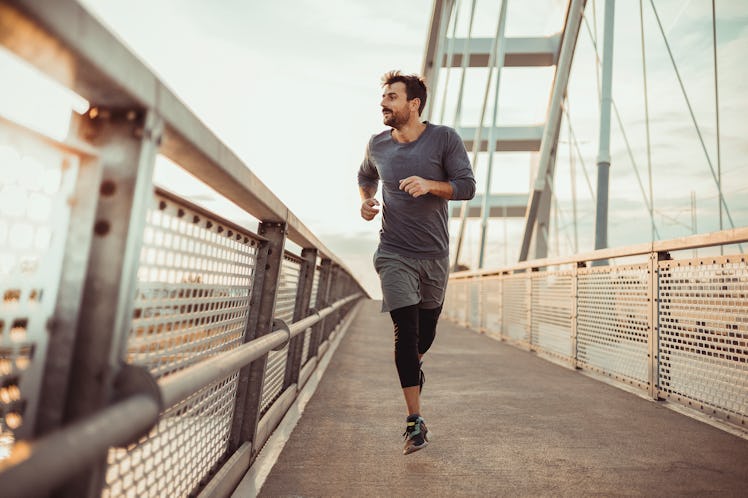 Athletic young man running on a bridge during sunset.