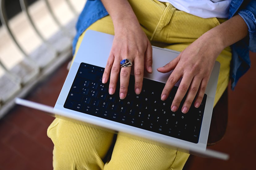 close up of female hands working on laptop keyboard. view from above.