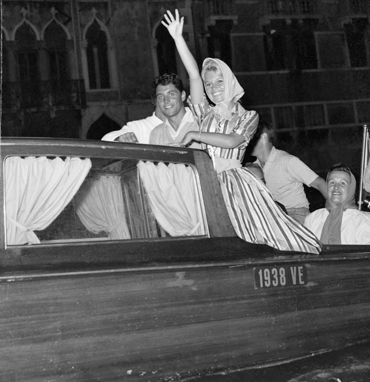 Brigitte Bardot waves to cheering fans as she rides a motor launch 