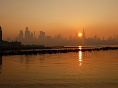 JERSEY CITY, NJ - JULY 5: Haze shrouds the skyline of midtown Manhattan as the sun rises behind the ...
