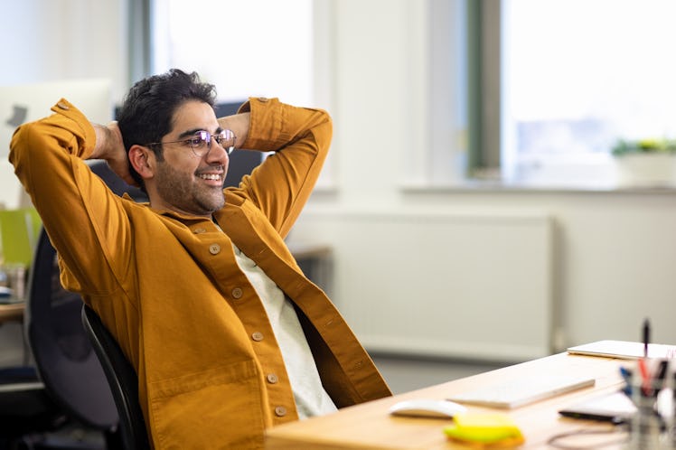 Employee in office leaning back in his chair and smiling.