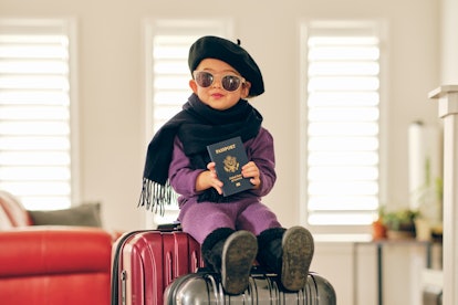A little girl traveler, sitting on suitcases in a home as she prepares to travel.