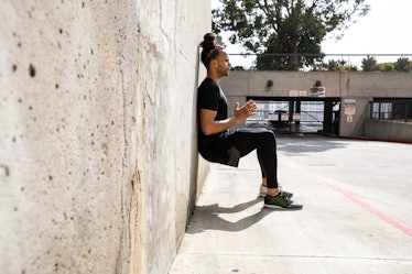 A man does a wall sit against a wall. Wall sits are the most effective isometric exercise for loweri...