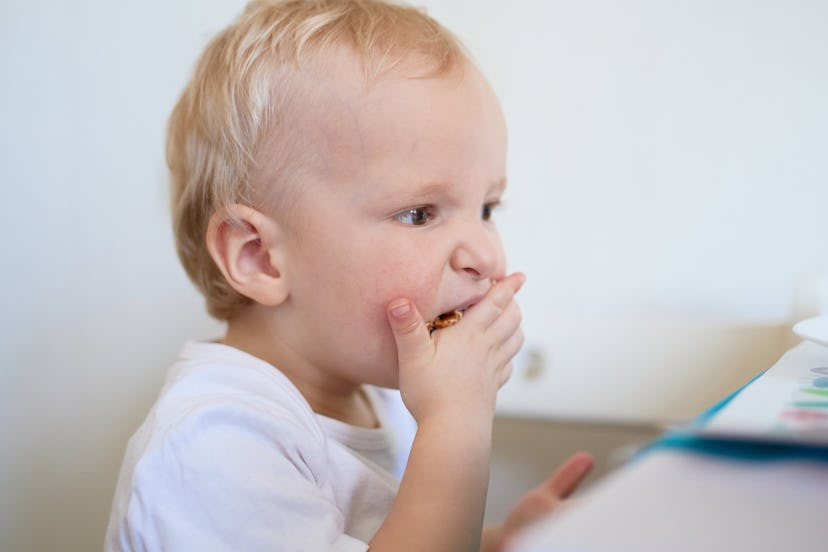 One-year-old boy eats pancakes with his hands