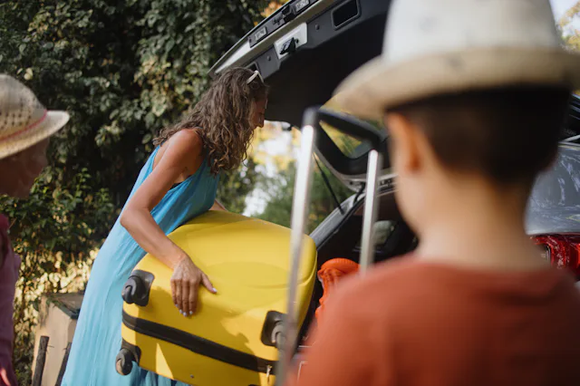 Mother packing car with two small children. Summer vacation concept, road trip