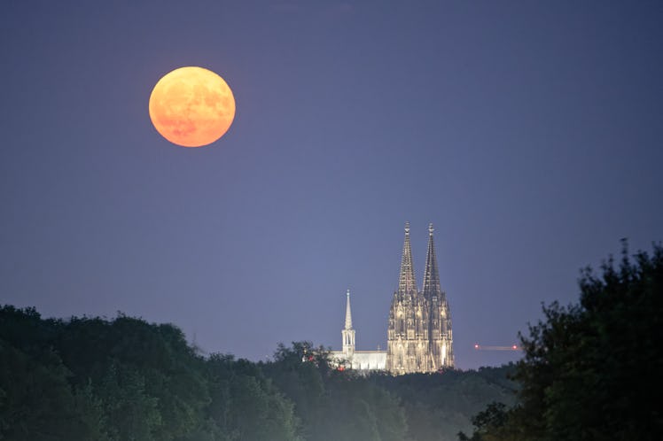 03 July 2023, North Rhine-Westphalia, Cologne: The full moon rises over the Cologne Cathedral. This ...
