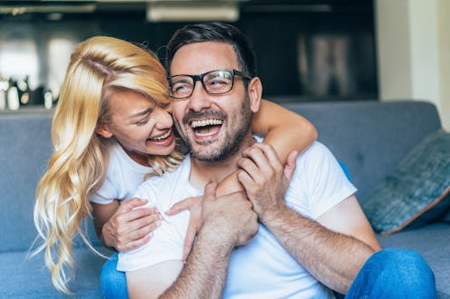 Happy young couple Looking happy and laughing. Shot of a young couple relaxing at home. Embraced cou...