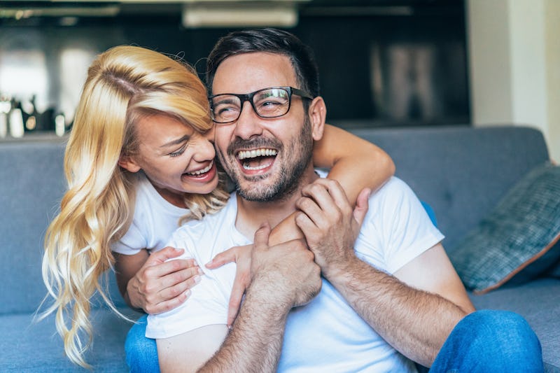 Happy young couple Looking happy and laughing. Shot of a young couple relaxing at home. Embraced cou...