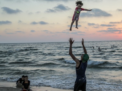 GAZA, PALESTINE - 2023/07/22: A Palestinian father plays with his child at the beach before sunset i...