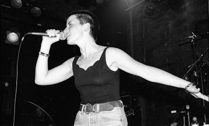Dolores O'Riordan of The Cranberries performs on stage, wearing a black tank top, holding a micropho...
