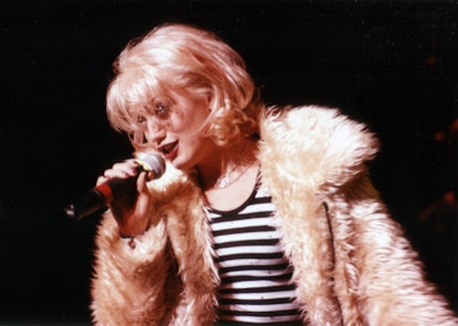Singer Gwen Stefani of No Doubt in a fur coat holding a microphone.
