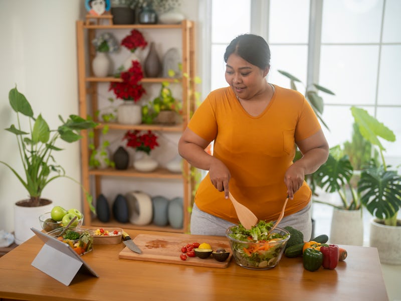 Plus size , caucasian woman learning to make salad and healthy food from social media