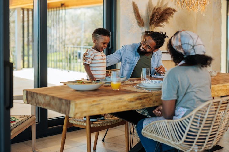 A young African American family is at home, bonding as they have lunch together in their modern dini...