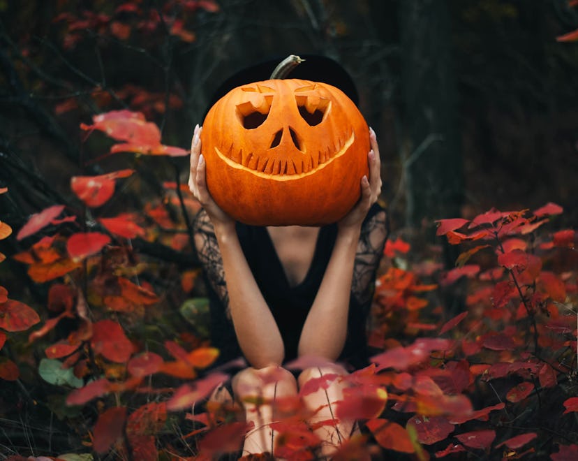 The girl sits in the forest and holds a pumpkin in her hands in halloween captions roundup